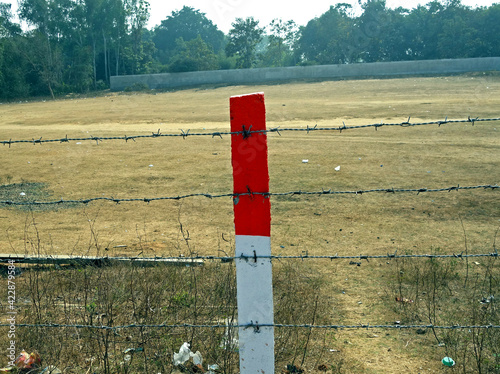 A red and white color concrete peg between a string fence