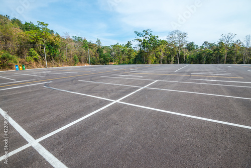 Empty space outdoor asphalt parking lot in national park. Large car park with white line paint on mountain hill in sunny day blue sky background.