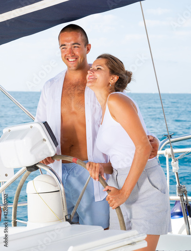 Loving couple steering yacht in calm blue ocean during romantic summer vacation © JackF