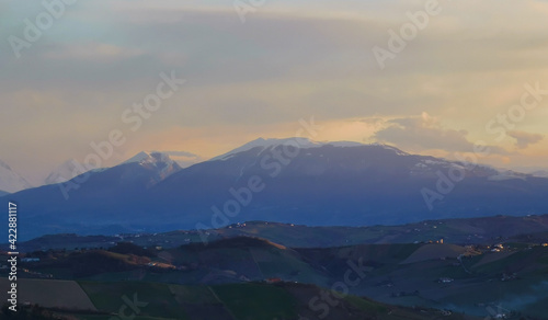 Tramonto di luce e foschia sulle cime innevate dell’appennino © GjGj