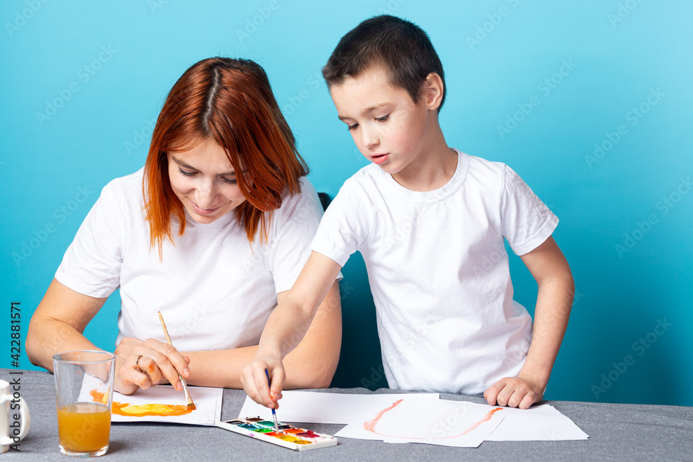 Children's creativity. mom and child son paint watercolor homework for kindergarten on blue background Children's creativity. mom and child son paint watercolor homework for kindergarten on blue background