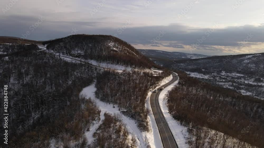 Ascending aerial view drone video on the curved serpentine road trough the trees and forest in mountain range with white snow in winter day near Knjazevac in Serbia - Travel journey vacation concept Ascending aerial view drone video on the curved serpentine road trough the trees and forest in mountain range with white snow in winter day near Knjazevac in Serbia - Travel journey vacation concept