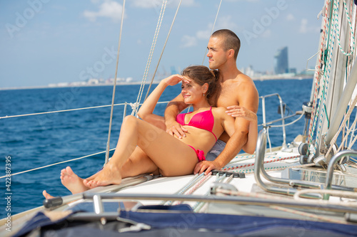 Young loving couple enjoying sea trip on pleasure sailboat along coast of Barcelona on sunny summer day © JackF