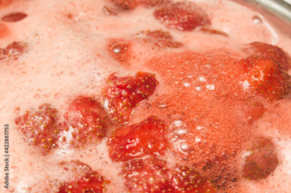 Fototapeta premium Red strawberry cooked in sugar syrup. Process of making jam marmalade at home.