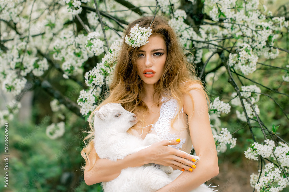 Fashion portrait of young beautiful woman holding a small lamb in spring blooming garden. Fashion portrait of young beautiful woman holding a small lamb in spring blooming garden.