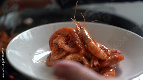 cook removing fried prawns from the heat during the preparation of fideua photo