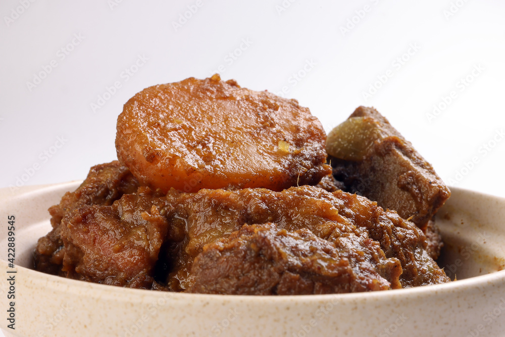 Asian style Beef bhuna dry curry with potato in ceramic bowl over white background