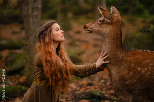 Redhead girl with deer in a long dress