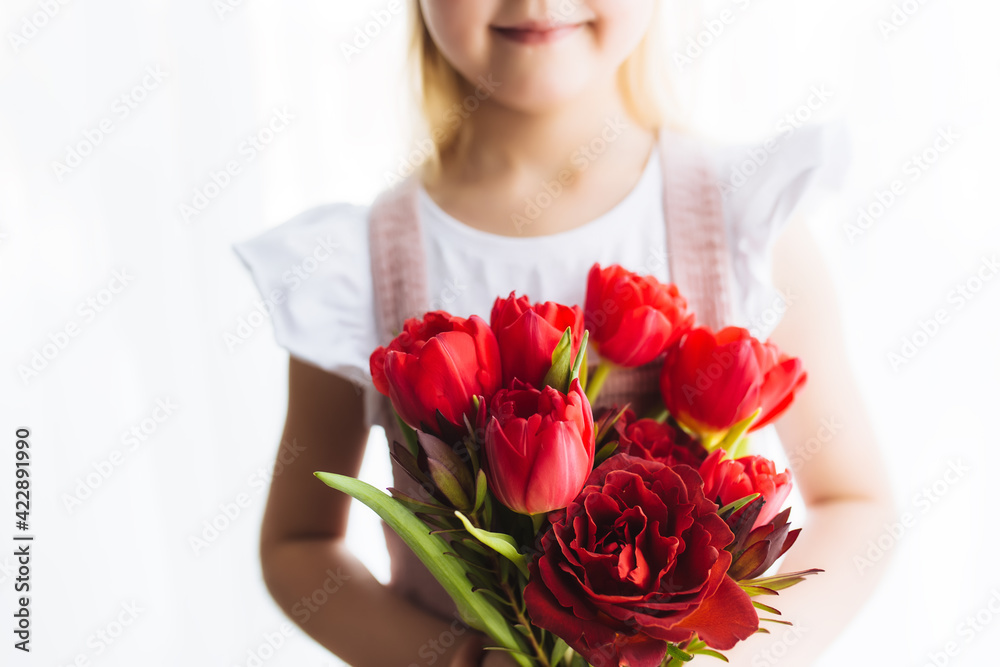 Smiling small girl holding bouquet of red tulips. Concept for greeting card