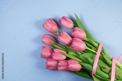 Fototapeta Naklejka Na Ścianę i Meble -  Pink tulips flowers on blue background. Card for Mothers day, 8 March, Happy Easter, Valentines Day, Birthday. Waiting for spring. Greeting card. Flat lay, top view, Copy space for text