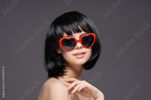 Beautiful woman in a wig dark glasses naked shoulders close-up