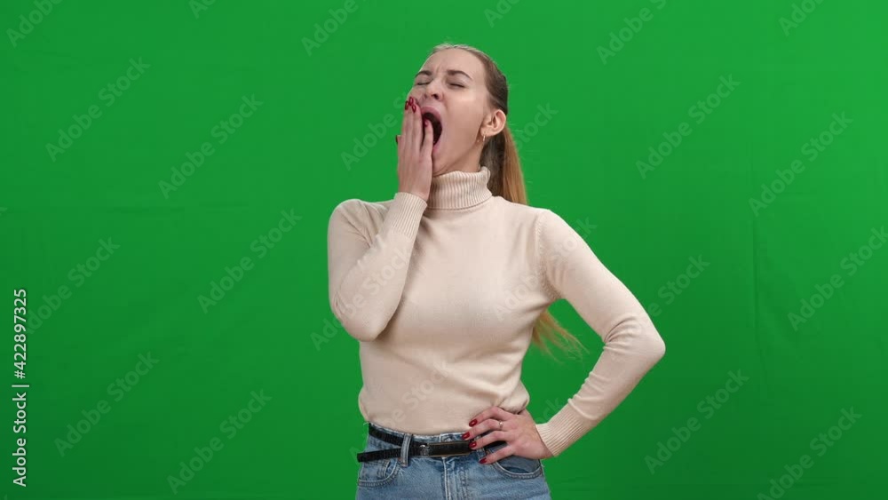 Exhausted young woman yawning at chromakey background. Portrait of tired Caucasian lady falling asleep on green screen. Tiredness and exhaustion concept. Exhausted young woman yawning at chromakey background. Portrait of tired Caucasian lady falling asleep on green screen. Tiredness and exhaustion concept.