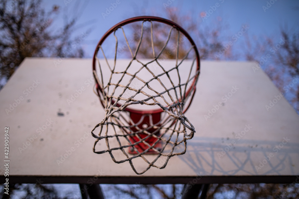 View on a basketball ring set on an outdoor playground from down below