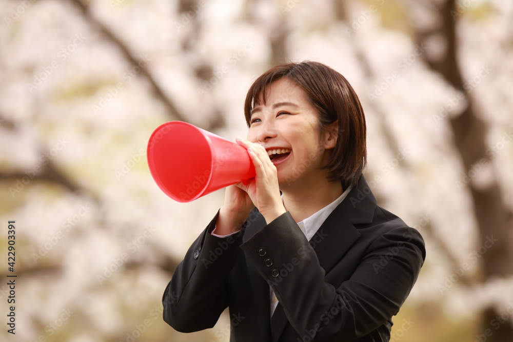 メガホンを持ち声援を送る女性社員 メガホンを持ち声援を送る女性社員