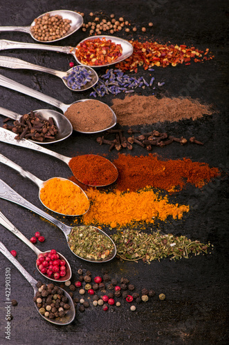 Fototapeta Naklejka Na Ścianę i Meble -  dried spices - pepper, turmeric, paprika, anise, lavender, adjika, cilantro in old spoons on a black background