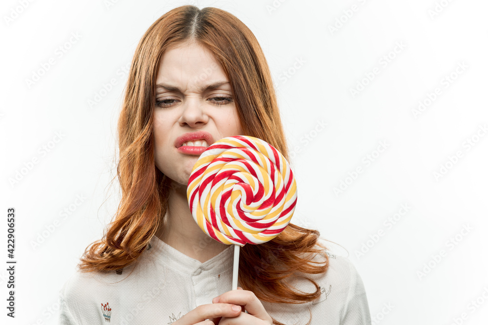 cheerful red-haired woman with a big lollipop in her hands emotions sweets lifestyle light background
