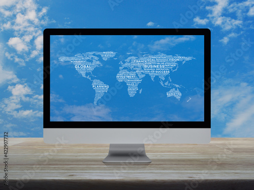 Global business words world map on desktop modern computer monitor screen on wooden table over blue sky with white clouds, Global business online concept, Elements of this image furnished by NASA