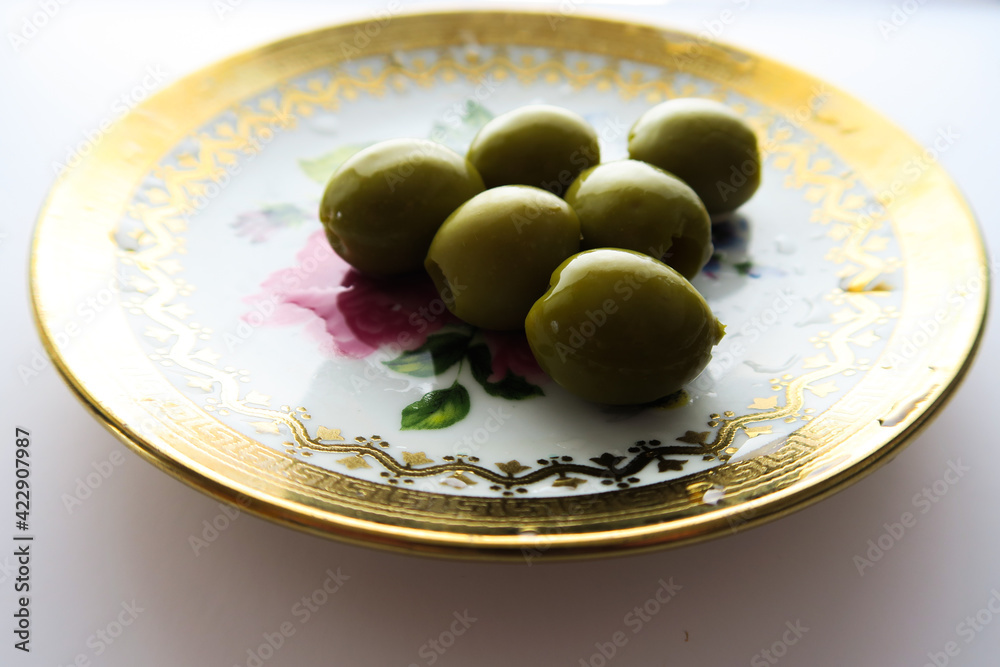 Mediterranean food, olives on a golden plate on a white background Mediterranean food, olives on a golden plate on a white background
