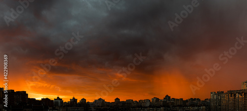Wide angle shot of dramatic stormy sunset sky with clouds over city skyline background.
