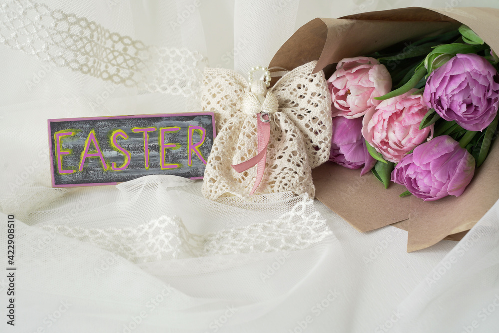 Delicate background with a bouquet of tulips, an angel of lace and a sign with the inscription Easter Delicate background with a bouquet of tulips, an angel of lace and a sign with the inscription Easter