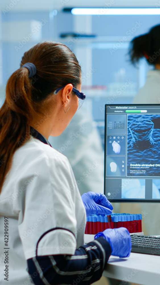 Laboratory doctor holding at blood sample and writing on computer while ...