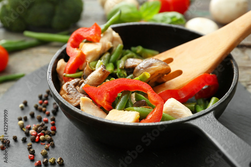 Frying pan with tasty vegetables and chicken on table, closeup