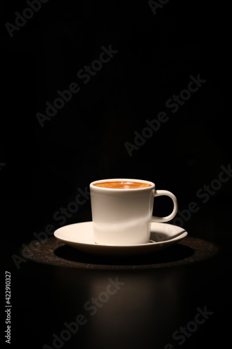 Cup with hot coffee on dark background