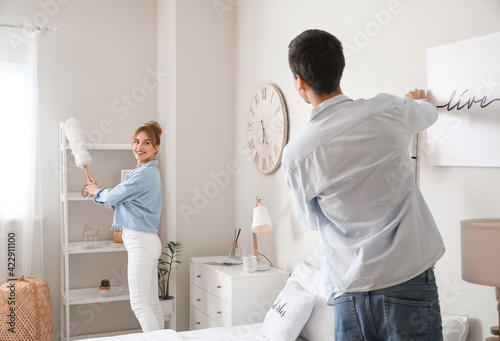 Young couple cleaning their bedroom