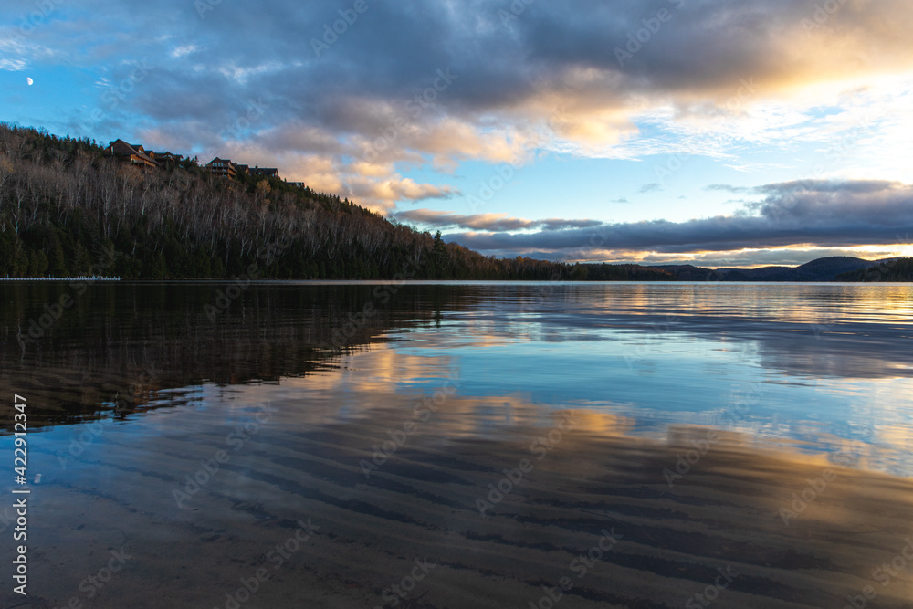 Fototapeta premium Coucher de soleil ennuagé avec lumière vive sur un lac miroir
