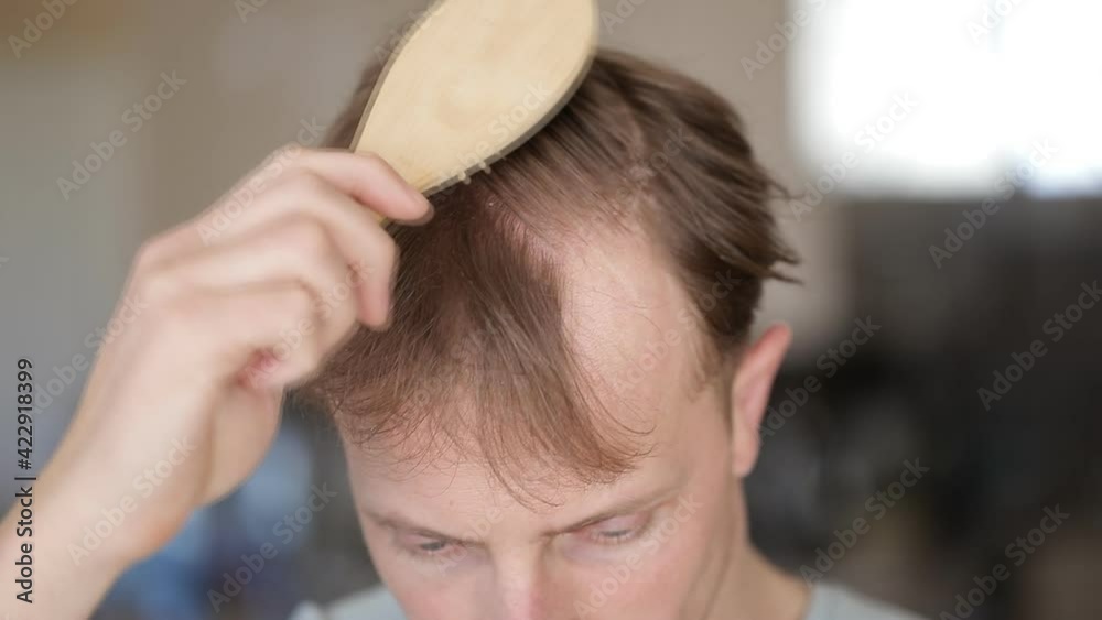 Portrait of handsome cheerful young man combing his hair
