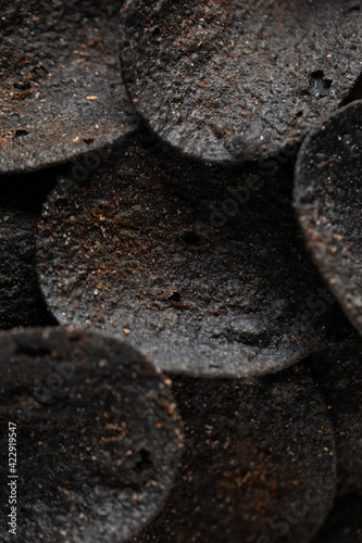 Stack of of black potato chips on concrete table. Unusual chips. Unhealthy eat. Junk food.