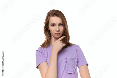 Portrait of cute thinking young woman holding arm on chin wear casual t shirt © AstiMak