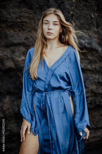 Photoshoot of a blonde girl in a blue dress on the Bali beach with black sand © Kate