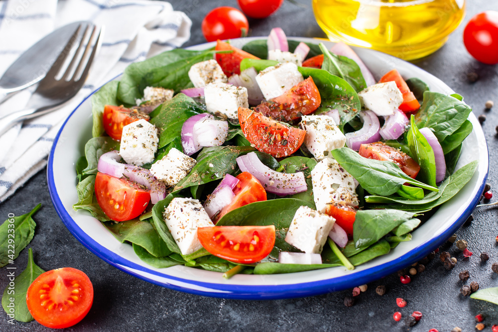 Healthy food. Greek salad with spinach, tomato, sweet pepper, red onion, feta cheese on a dark background Healthy food. Greek salad with spinach, tomato, sweet pepper, red onion, feta cheese on a dark background
