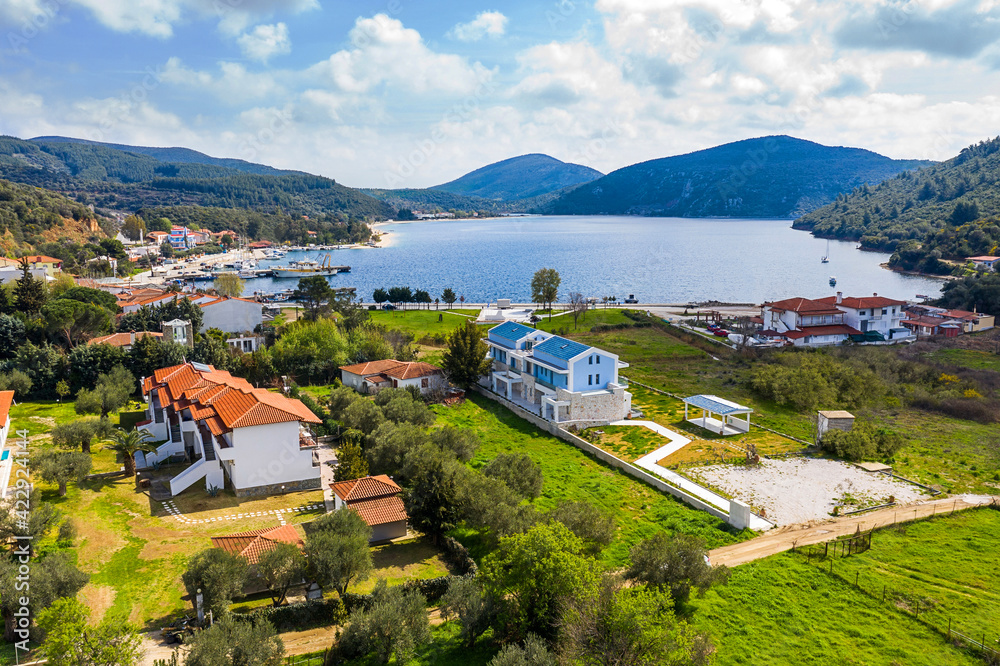 Obraz premium Drone top view of Europe rural landscape with countryside village by forest lake valley. Aerial panorama of white residential houses among Greece green olive garden hills