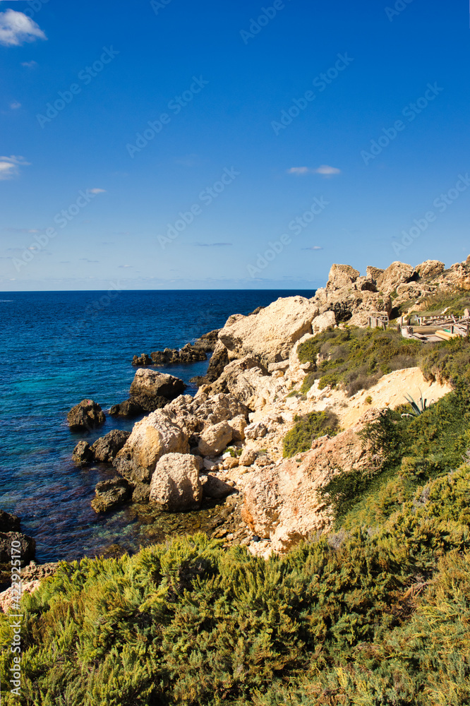 Small cliffs and a rocky shore at Prajjet Bay or Anchor Bay at Popeye Village in Malta.