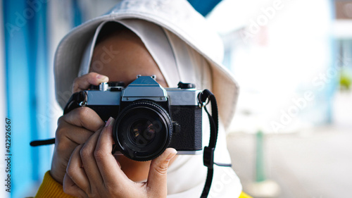 an Asian woman traveler in keraton solo wearing jilbab and analog camera