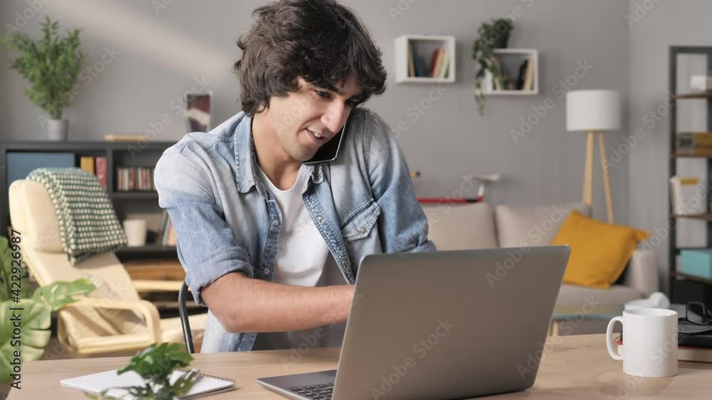 man sits at his desk having conversation at the phone talking with customer assistance service,young arab male at the laptop working from home,gives remote support to client speaking at the telephone man sits at his desk having conversation at the phone talking with customer assistance service,young arab male at the laptop working from home,gives remote support to client speaking at the telephone