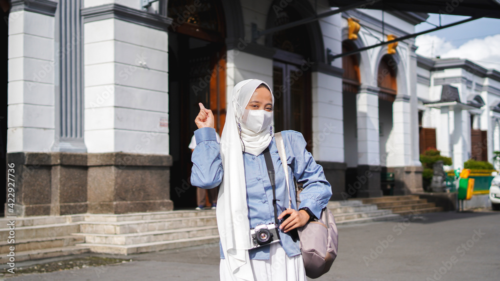 Asian women traveling by train in front of the station wearing jilbab and analog camera
