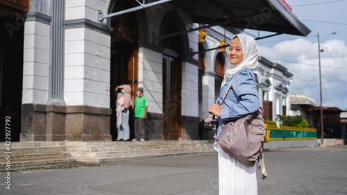 Asian women traveling by train in front of the station wearing jilbab and analog camera photo