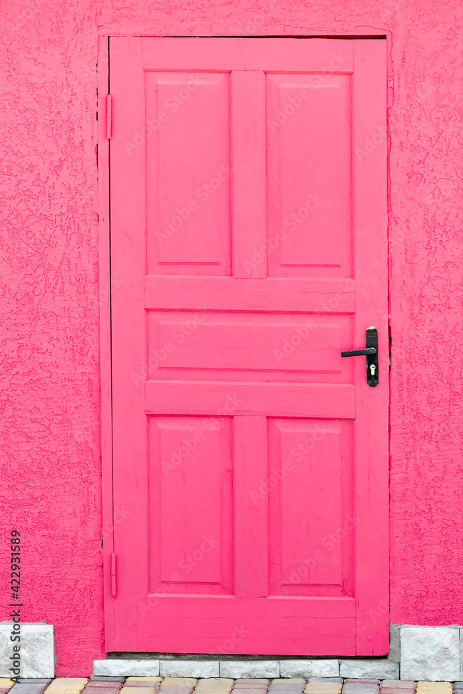 A pink wooden door. View from the front under the bright daylight sun.