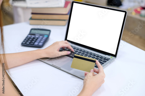 Close up of woman with a credit card to do shopping online using laptop at office. Mock up.