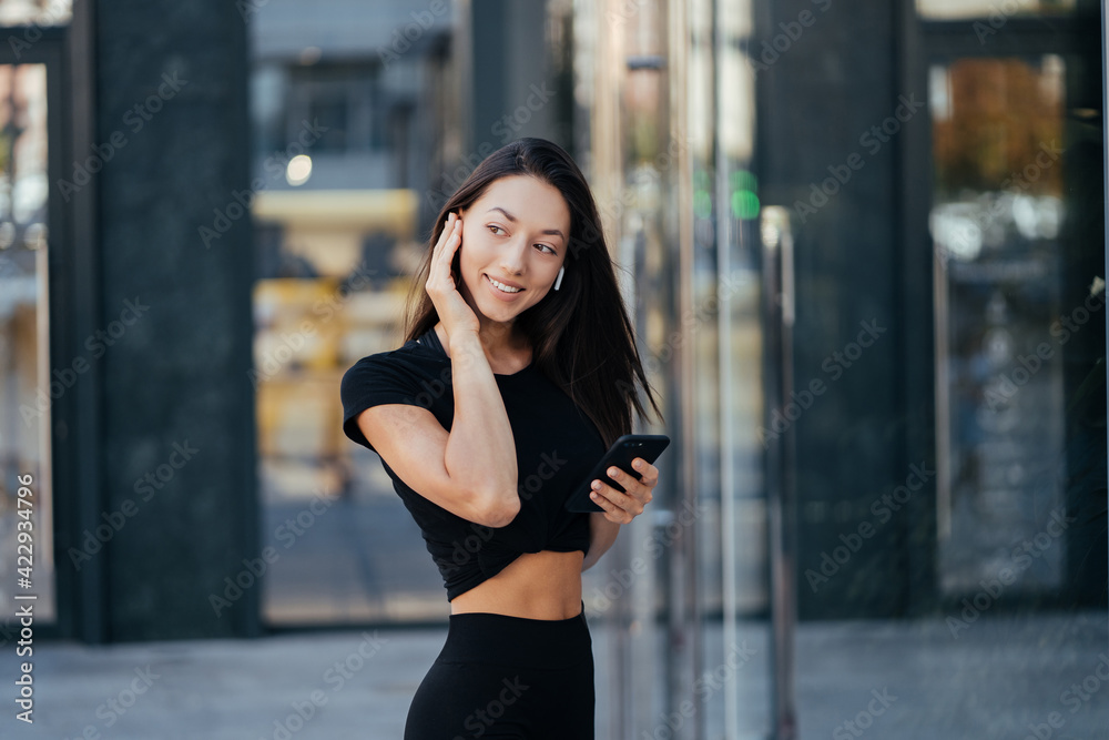 Portrait of a young brunette woman with headphones while walking