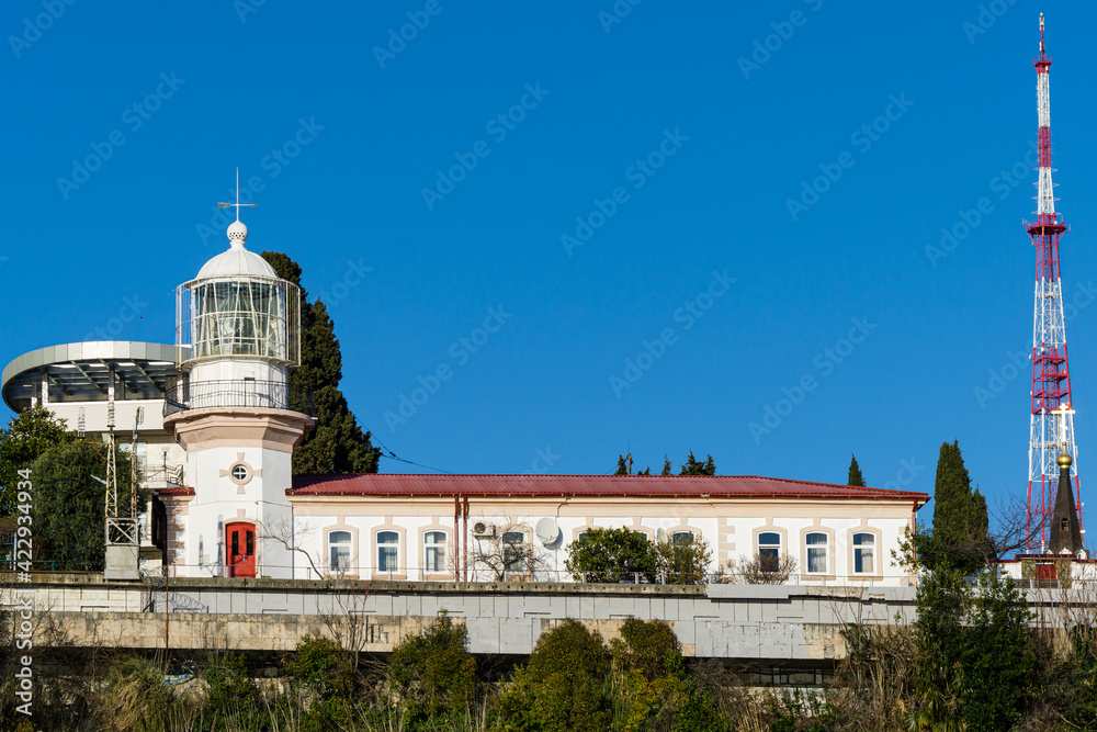 View of old lighthouse nearby Commercial seaport in Sochi city center on sunny winter day. Sochi, Russia - March 14, 2021
