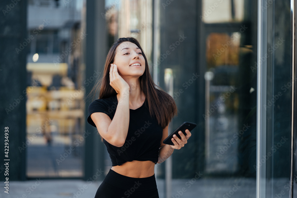 Fototapeta premium Portrait of a young brunette woman with headphones while walking