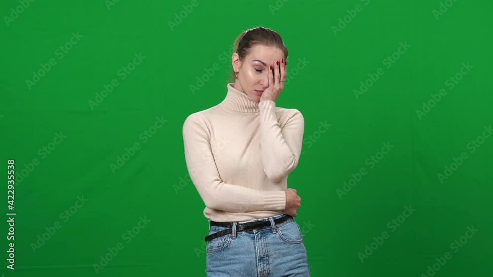 Portrait of young shocked woman holding face with hand looking at camera. Dazed Caucasian slim lady with surprised facial expression at green screen chromakey background. Portrait of young shocked woman holding face with hand looking at camera. Dazed Caucasian slim lady with surprised facial expression at green screen chromakey background.