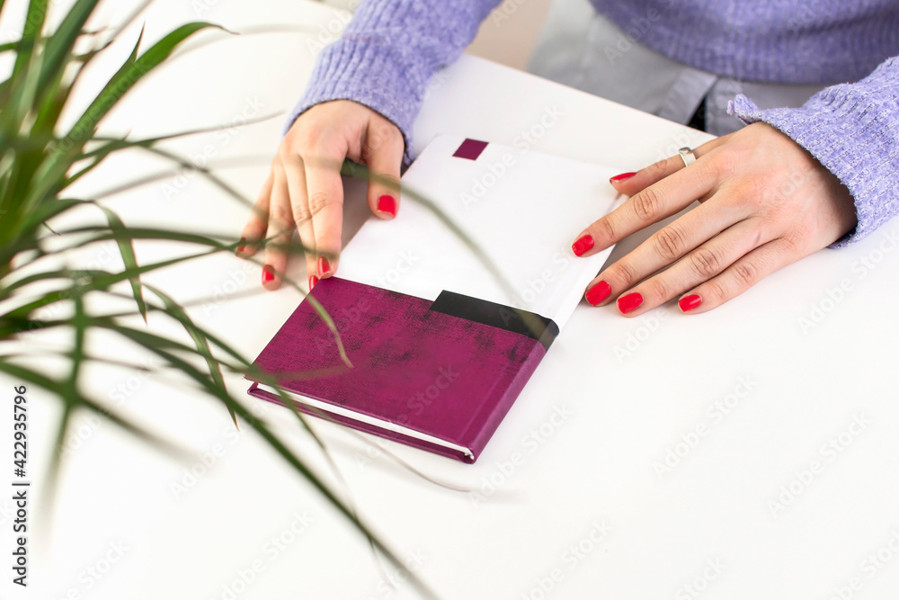 Woman holding book on white office table. Top view of female hands holding a book. Woman holding book on white office table. Top view of female hands holding a book.