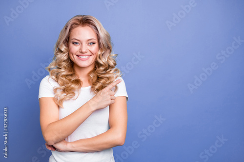 Photo of young happy cheerful lovely pretty charming girl point finger copyspace advertise isolated on blue color background