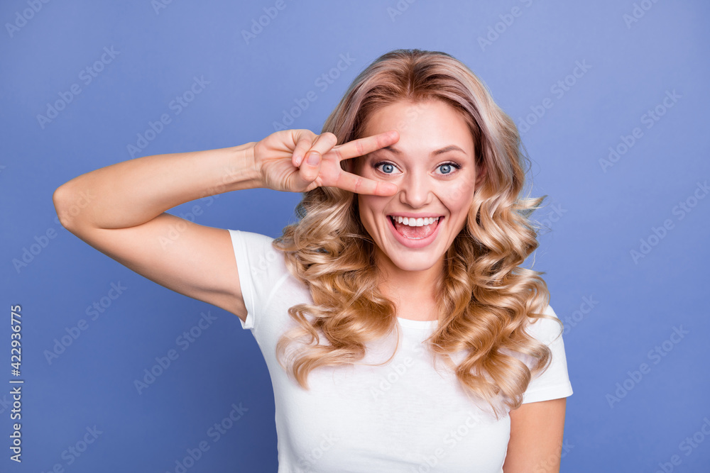 Photo of young beautiful attractive pretty smiling excited girl showing v-sign on eye isolated on blue color background