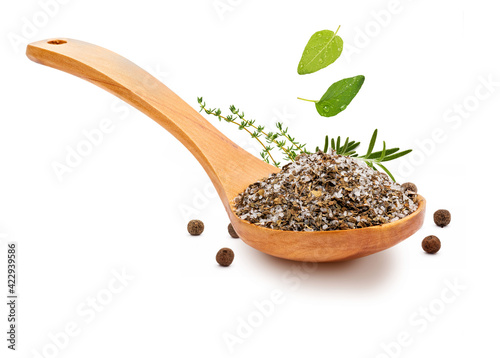 Fine and white salt with fine herbs, with various spices (rosemary, oregano and black pepper) in a wooden spoon (salt varieties collection). Isolated on white background Rustic appearance